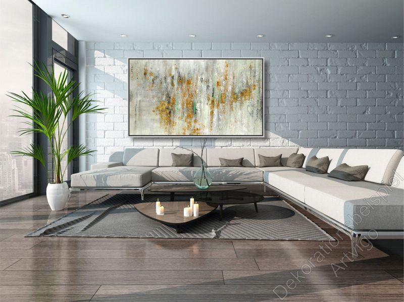 Sitzecke mit vielen warmen Farben. Über dem Sofa hängt ein großes eingerahmtes Bild als Dekoration