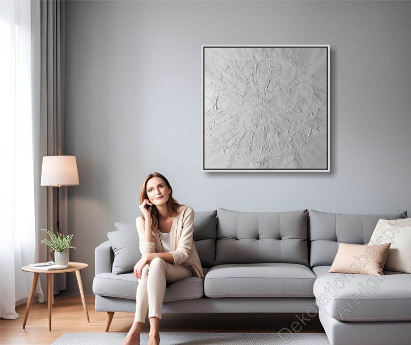 Heller Raum. Zur Dekoration hängt ein gegenstandsloses Bild mit Bilderrahmen an der grauen Wand