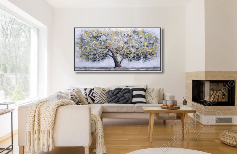 Wohnzimmer mit Eckkamin. An der Wand hängt ein Ölgemälde von einem großen Baum im Bilderrahmen