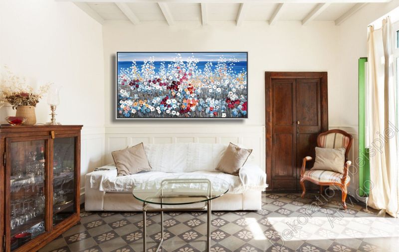 Gemütliches Wohnzimmer. Über dem Sofa hängt ein Kunstwerk von einer farbenfrohen Küste