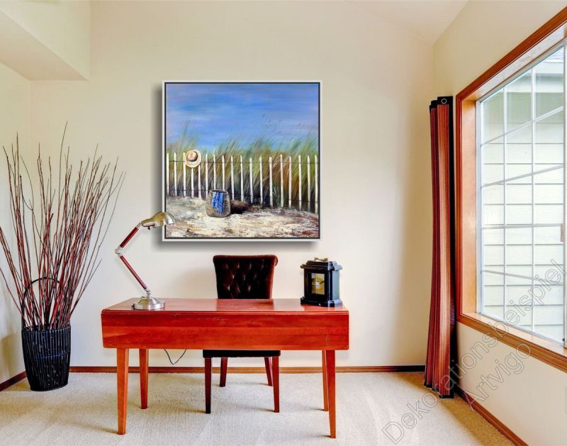 Arbeitszimmer mit einem roten Schreibtisch und sonnigem, unaufgeregten Strandbild in Bilderrahmen